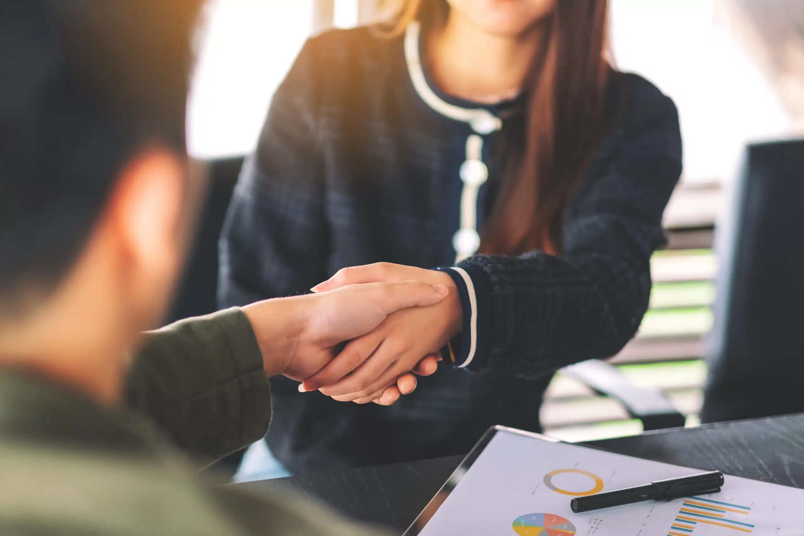 Closeup image of two businesspeople shaking hands in a meeting